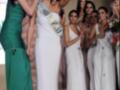 Una mujer con un vestido verde y una corona en la cabeza celebra junto a otras mujeres vestidas de blanco. La escena parece ser parte de un concurso o evento de belleza.