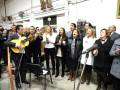 Un grupo de personas cantando y tocando música en una sala llena de decoraciones navideñas.