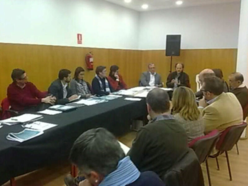 Reunión de trabajo en una sala con personas sentadas alrededor de una mesa.