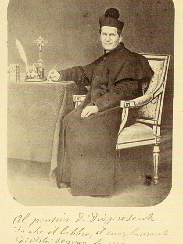 Retrato de un sacerdote sentado en una silla, con un libro abierto sobre una mesa a su lado, posiblemente de fines del siglo XIX.