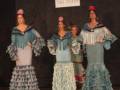 Tres modelos presentan trajes de flamenca en un desfile de moda tradicional española.