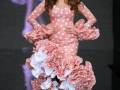 Una modelo presenta un vestido de flamenca rosa con lunares blancos y volantes en la falda, diseñado por Dolce & Gabbana.