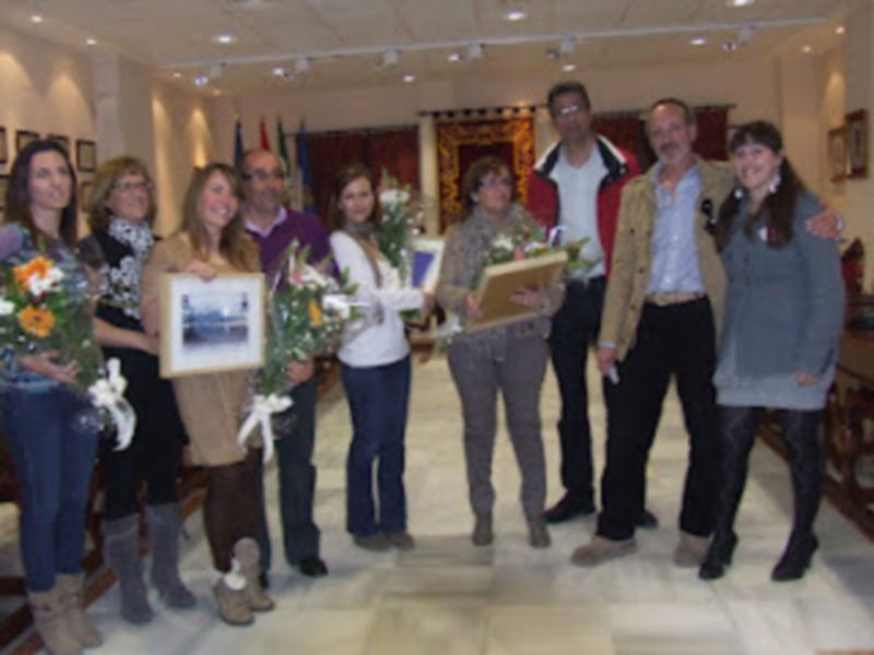 Celebración de un evento con personas sosteniendo flores y certificados en un ambiente acogedor.