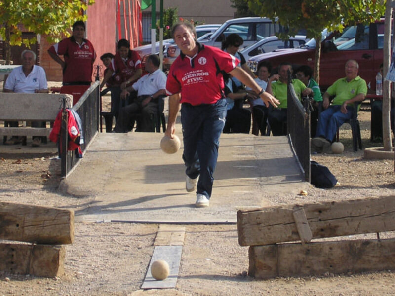 Un jugador participa en una partida de boliche, lanzando una bola hacia el objetivo.
