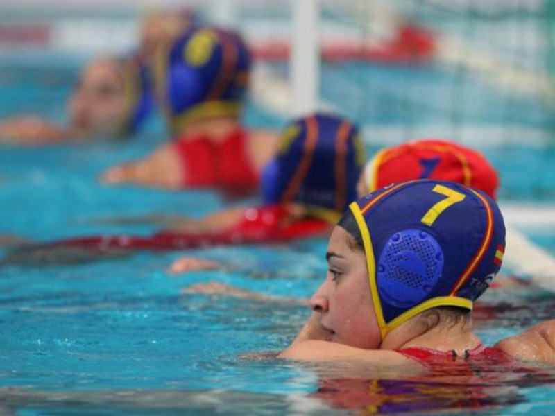 Jugadoras de waterpolo en acción durante un partido en una piscina.