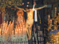 Una procesión religiosa con personas vestidas con trajes tradicionales, rodeadas de velas y flores, en un ambiente festivo y ceremonial.