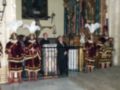 Celebración religiosa en una iglesia con personas vestidas con trajes históricos y un sacerdote oficiando el servicio.