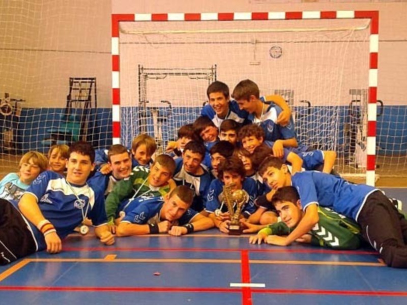 Equipo de fútbol sala celebrando con el trofeo en un polideportivo.