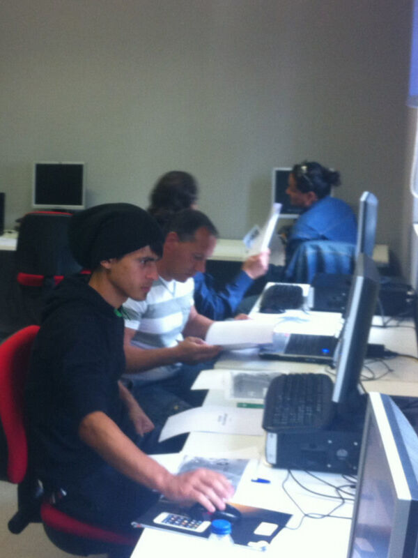Dos personas trabajando en un escritorio con computadoras y documentos.