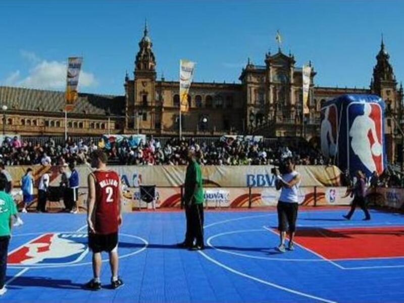 Pista de baloncesto en Plaza de España, Sevilla, con el escudo de la NBA en el fondo.