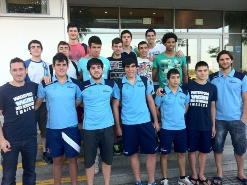 Equipo de waterpolo posando en la entrada de un edificio.