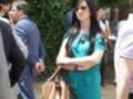 Una mujer con vestido verde y gafas de sol, caminando entre otros.
