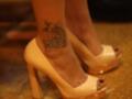 Tatuaje en el tobillo de una persona con tacones altos y plataforma.