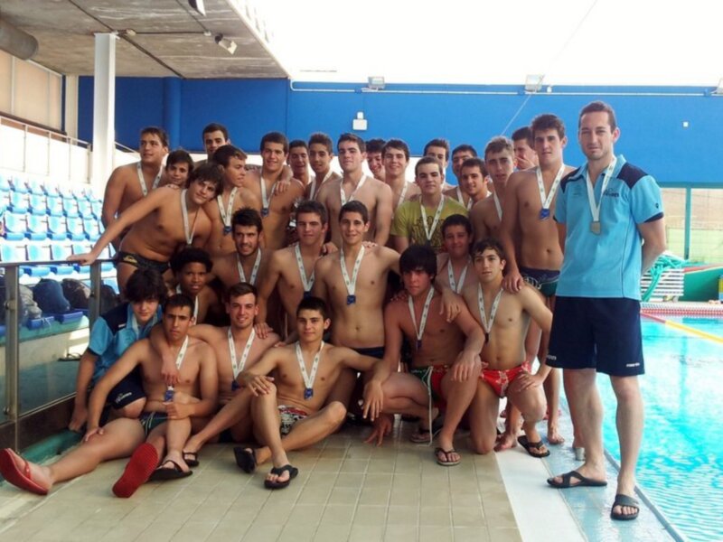 Equipo de natación posando con medallas en la piscina.