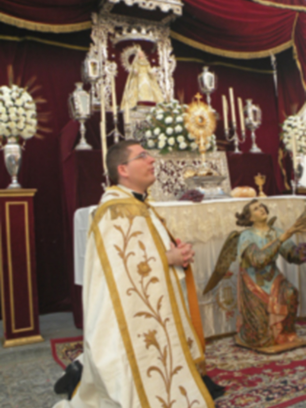 Un sacerdote en traje sacerdotal celebra una misa en un altar adornado con flores y una imagen de la Virgen María.