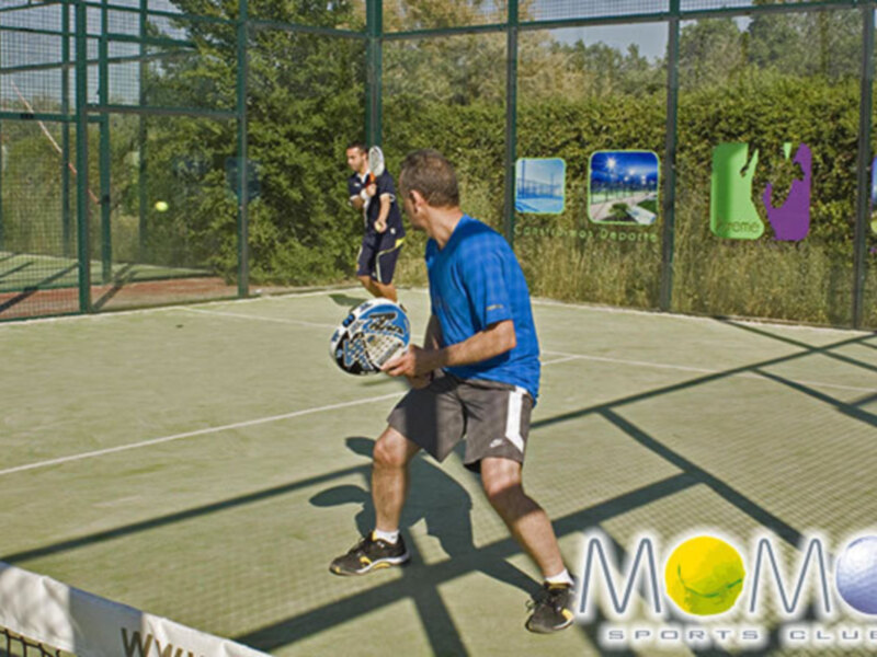 Jugadores de pádel en acción en una cancha deportiva al aire libre.