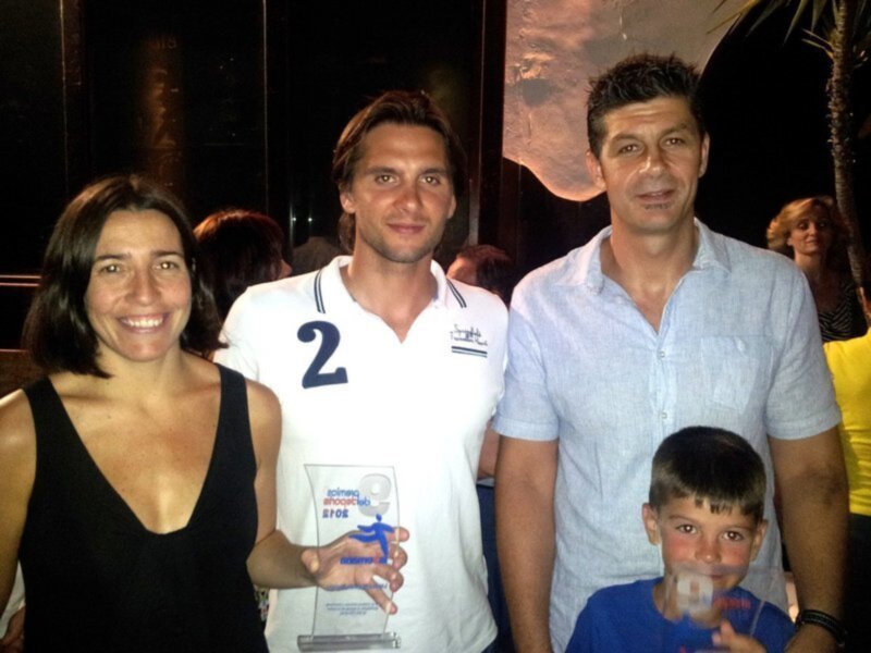 Una familia feliz posando con un premio en una fiesta nocturna.