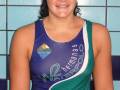 Una joven con una camiseta de waterpolo azul y verde, con el logo de Waterpolo Hermanas en la parte superior. El fondo es azul con un patrón de cuadros.