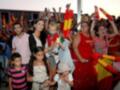 Gente celebrando con banderas españolas y globos de colores en un evento deportivo.