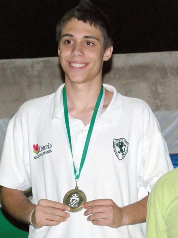 Joven sonriente con medalla en el cuello, camiseta blanca con logo 'Cazorla Naturalmania'.
