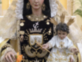 Imagen de una Virgen con un niño en sus brazos, vestida con trajes tradicionales y adornada con joyas.