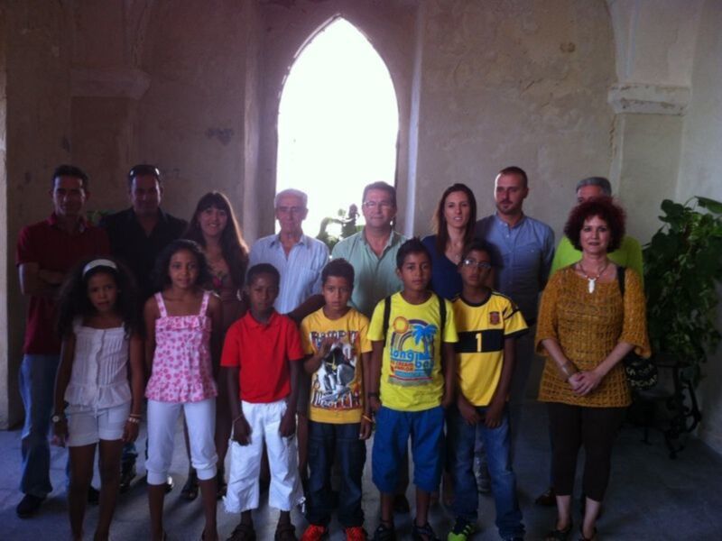Grupo de personas posando en un interior con arco gótico, incluyendo niños y adultos.