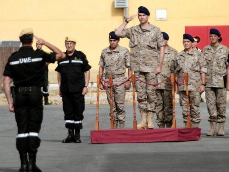 Desfile militar con oficiales saludando y soldados en uniforme de camuflaje.