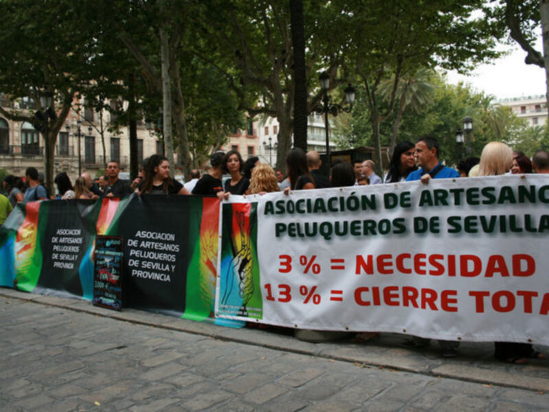 Manifestación de peluqueros en Sevilla con pancartas de protesta.}