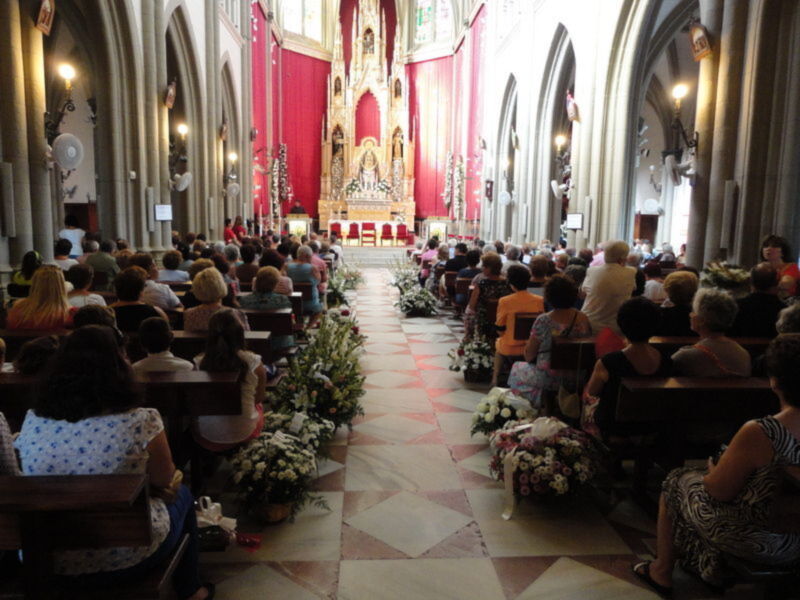 Interior de una iglesia con altares decorados y personas asistiendo a una ceremonia.