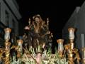 Procesión nocturna con una imagen religiosa adornada con flores y candelabros dorados.