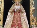 Imagen de una Virgen María en vestimenta tradicional, rodeada por flores y adorna dorado.