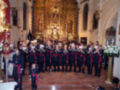 Un grupo de personas vestidas con uniformes militares posan frente a un altar elaborado en una iglesia. El ambiente es solemnemente decorado con flores y adornos religiosos, destacando la importancia de la celebración.