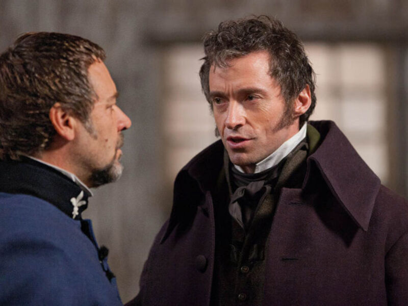 Dos hombres en trajes victorianos conversando en un entorno urbano.