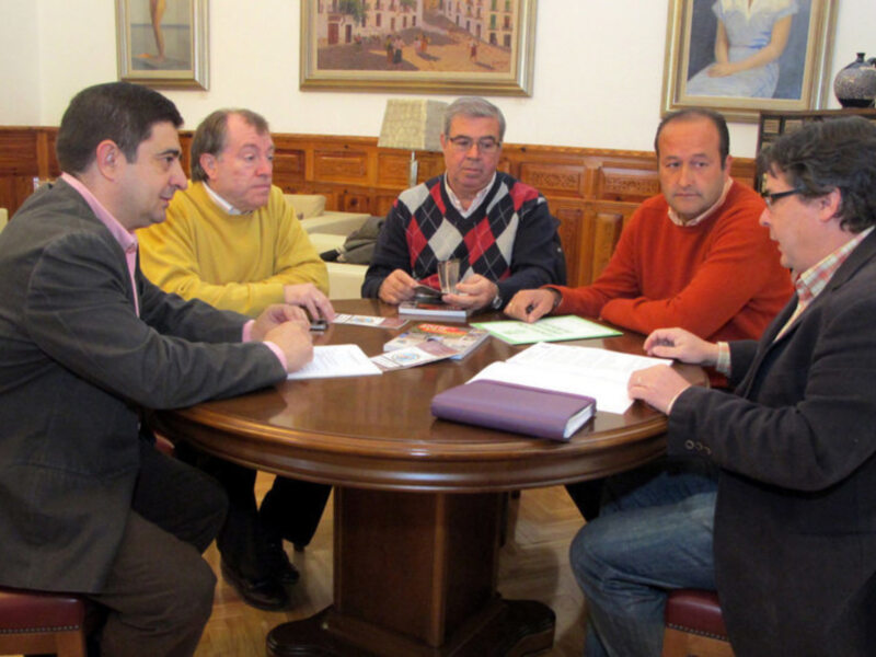 Reunión de trabajo en una sala con mesa redonda y documentos en la mesa.