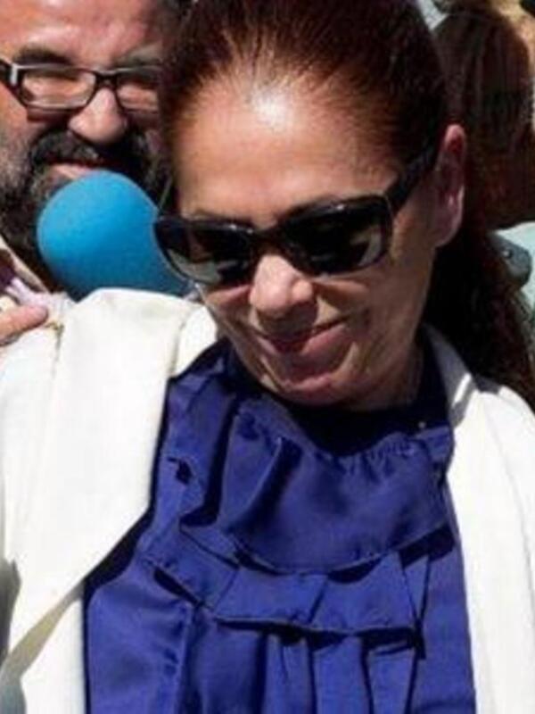 Una mujer con gafas de sol y una falda azul, posiblemente en un evento público.