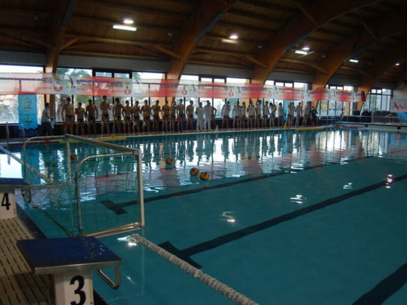 Equipo de waterpolo en línea en una piscina cubierta, listos para un partido.