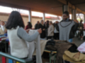 Mercado de ropa usada con personas examinando y seleccionando prendas.