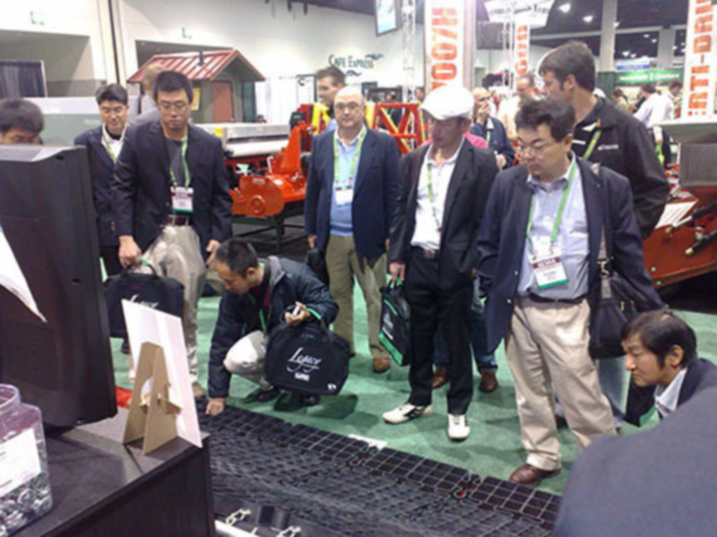 Exposición de tecnología agrícola en una feria internacional, con visitantes examinando un sistema de riego y otros equipos agrícolas.