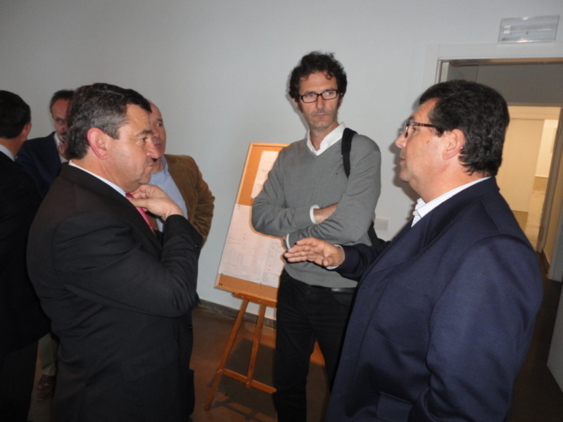 Conversación en una reunión profesional con paneles informativos en el fondo.
