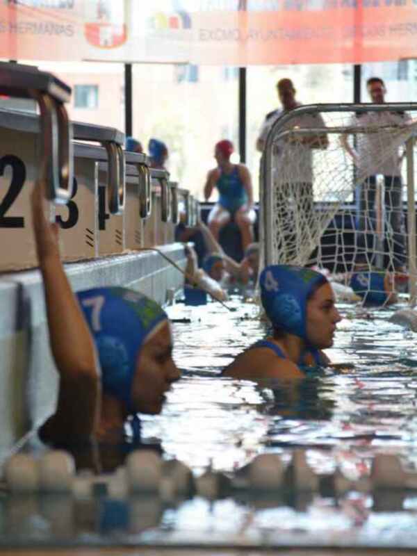 Jugadoras de waterpolo en piscina, preparándose para un partido.