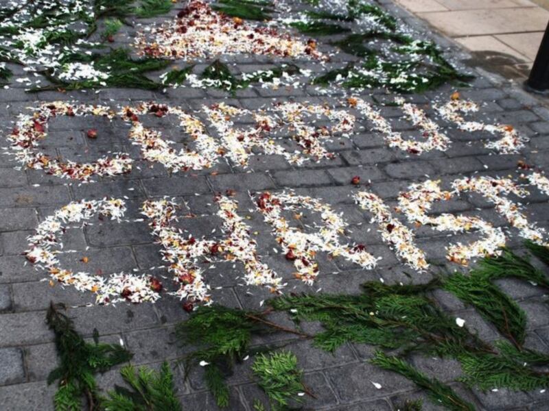 Mensaje floral 'STOP AIDS' en el suelo, con hojas y flores.
