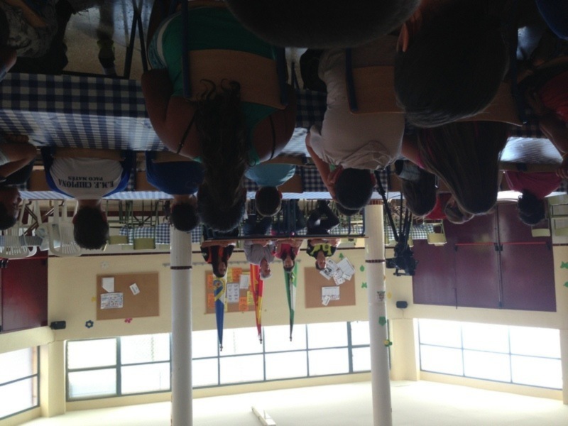 Alumnos participando en una actividad de aprendizaje en un aula bien iluminada con banderas de países y tableros de anuncios.