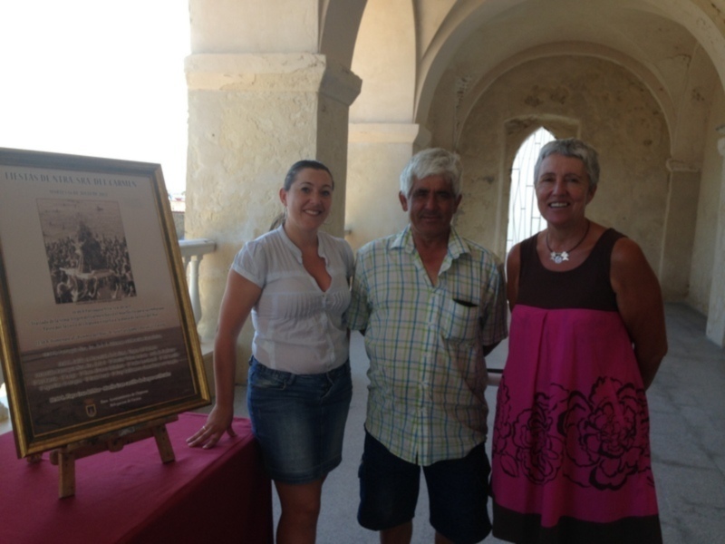 Tres personas posan junto a una placa conmemorativa en un patio con arcos, probablemente en un lugar histórico.