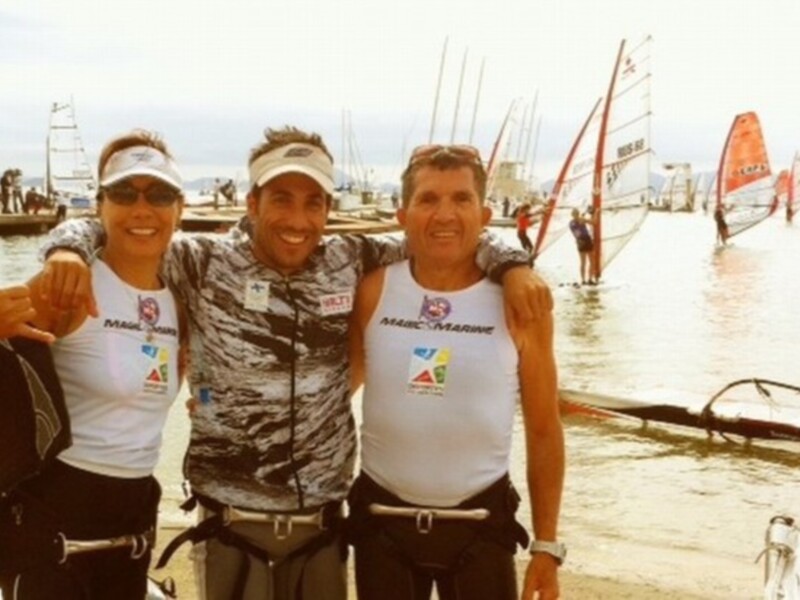Equipo de windsurfing posa juntos en la costa, listos para la acción.