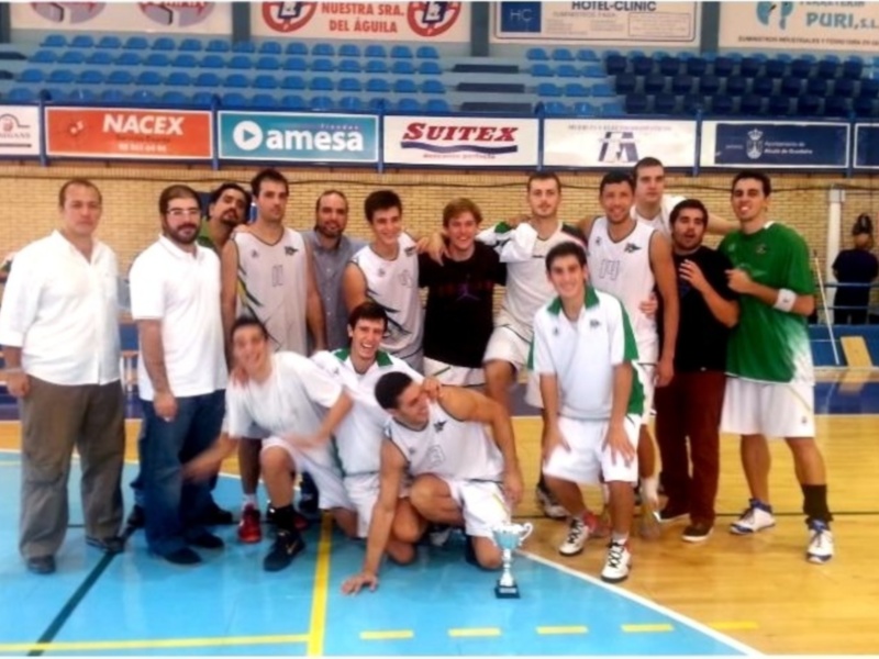Equipo de baloncesto posando con el trofeo en una cancha deportiva.