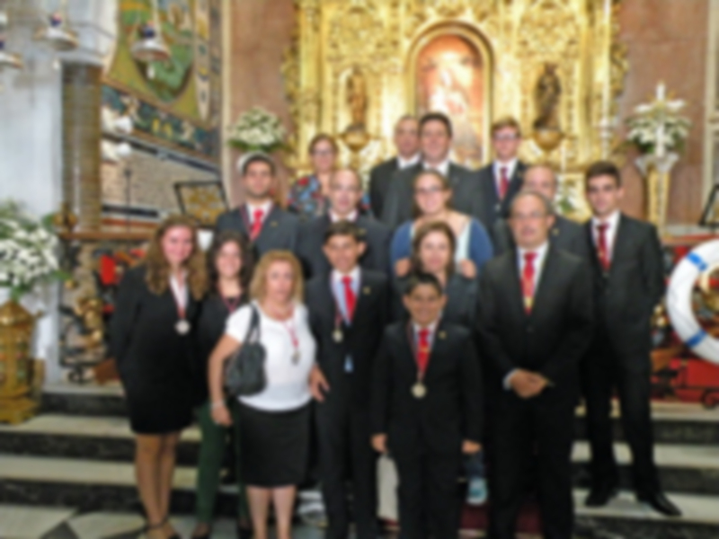 Un grupo de personas posando para una foto en una iglesia, vestidas con trajes formales.