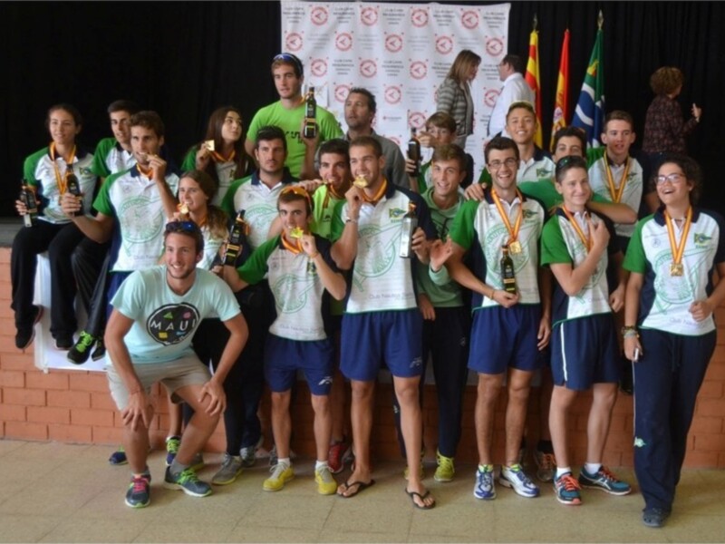 Equipo deportivo con medallas y trofeos celebrando un logro en un evento deportivo.