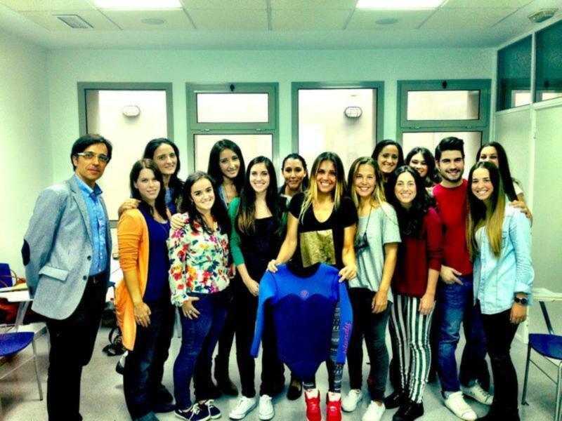 Grupo de estudiantes y profesor sonriendo en una aula, celebrando un logro o evento académico.