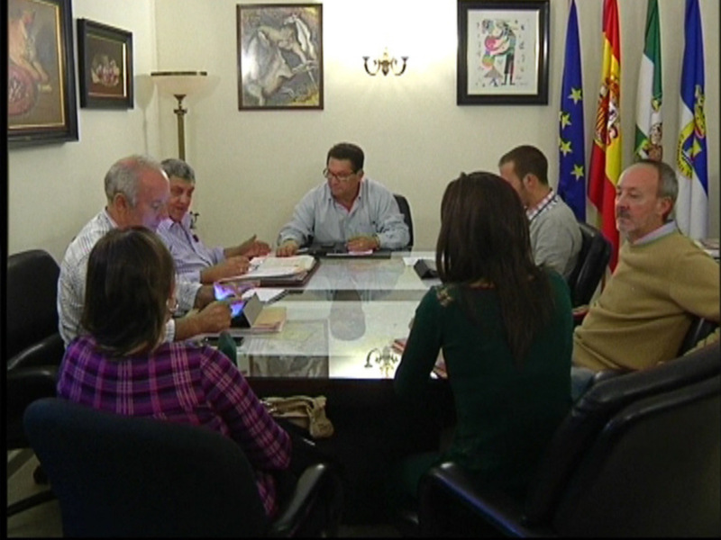 Reunión de trabajo en una sala con banderas y cuadros en la pared.