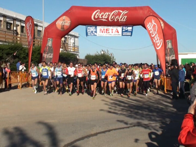 Atletas corriendo bajo la meta de una carrera con arco de Coca-Cola.